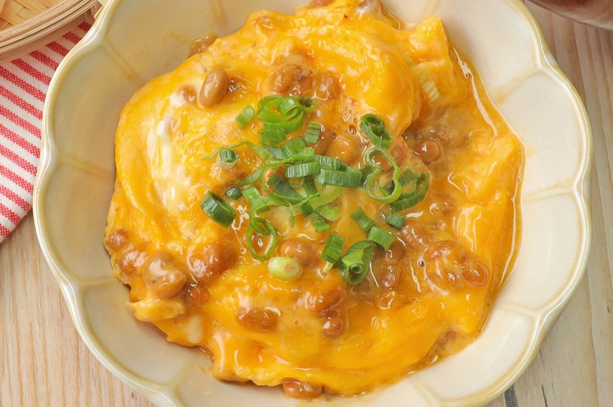 卵と納豆をトッピングしたご飯。鮮やかな緑のネギが飾られている。