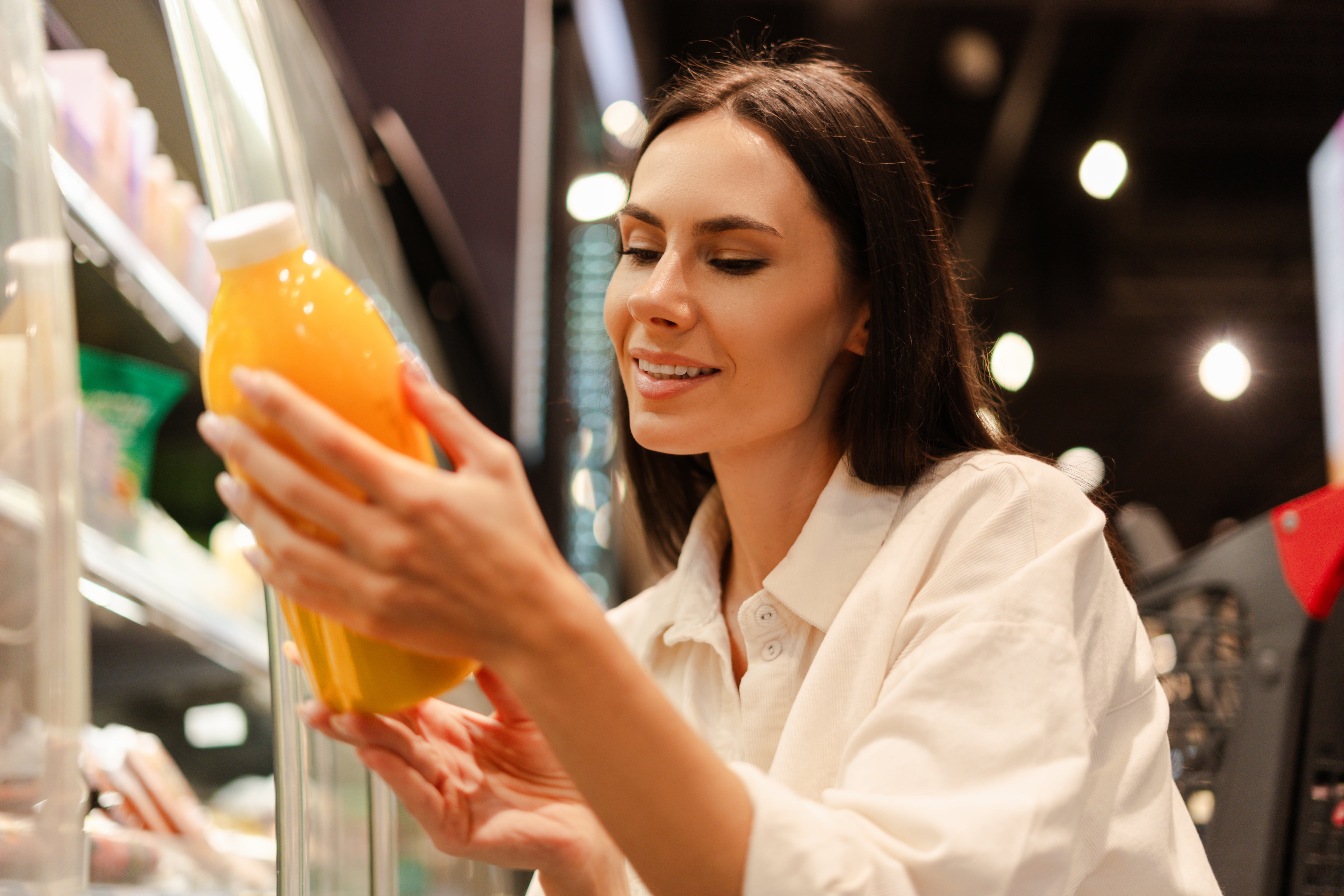 En person i en butikk smiler mens han undersøker en drikkeflaske, muligens handler juice