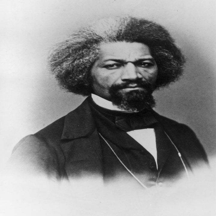 A historical figure with a serious expression, wearing a formal suit and bow tie, with distinctively styled hair
