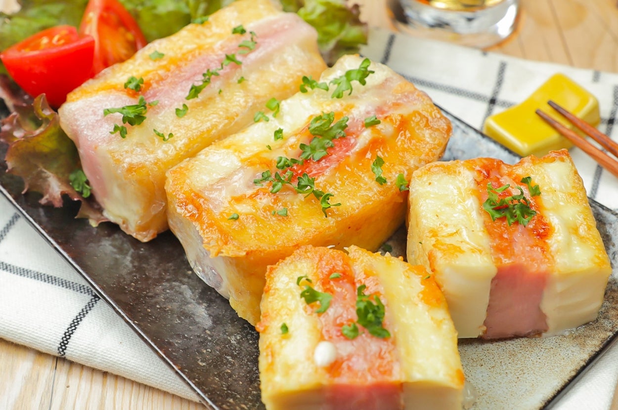 お皿に盛られたハムとチーズのサンドイッチ風料理。上にはパセリが散らされています。トマトとレタスが付け合わされています。