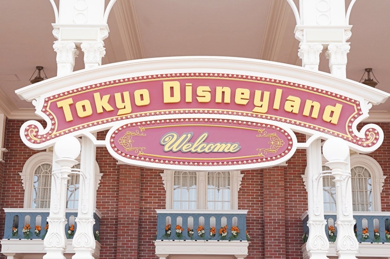 東京ディズニーランドの入口サイン。建物には装飾的なアーチと柱がある。