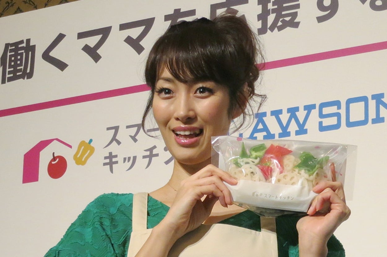 日本の若い女性がエプロン姿でスマートキッチンの料理を持っています。