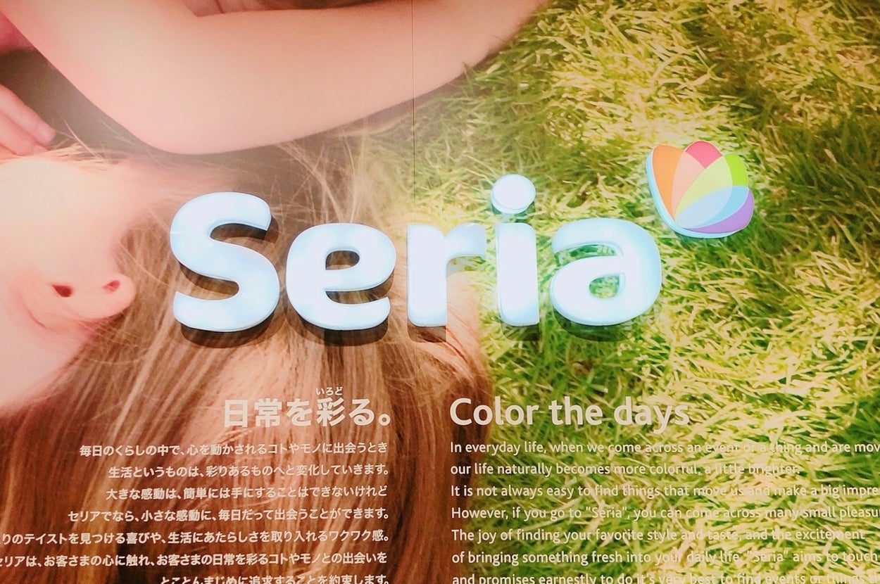 屋外の芝生に横たわる女性の上に「Seria」と大きく書かれている広告イメージ。