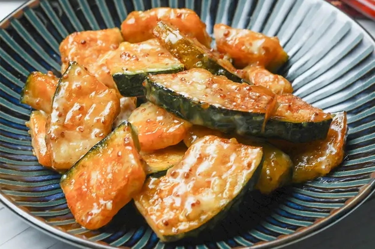 かぼちゃのマヨマスタード和えの料理。背景には赤い布と箸が置かれている。