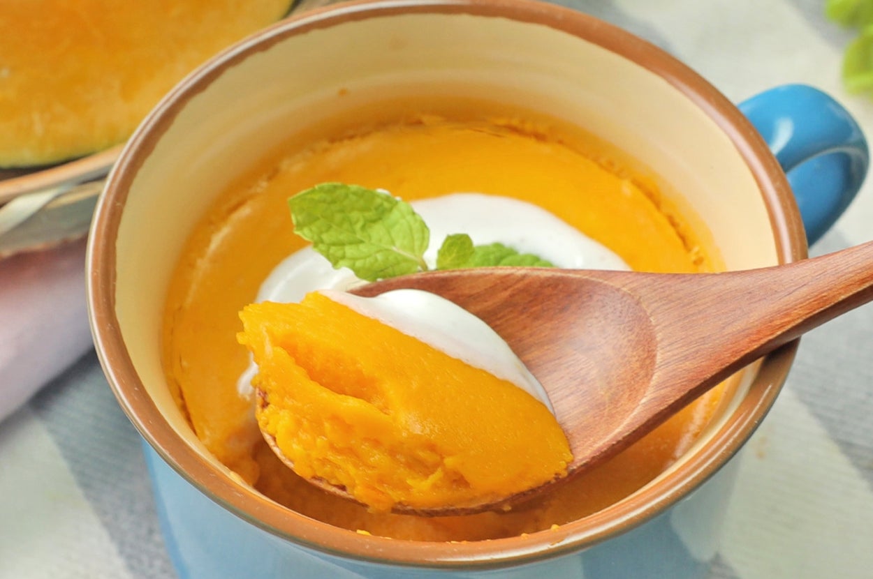 カップに入ったスイートポテトプリンがスプーンですくわれている。上にはホイップクリームとミントの葉がのっている。