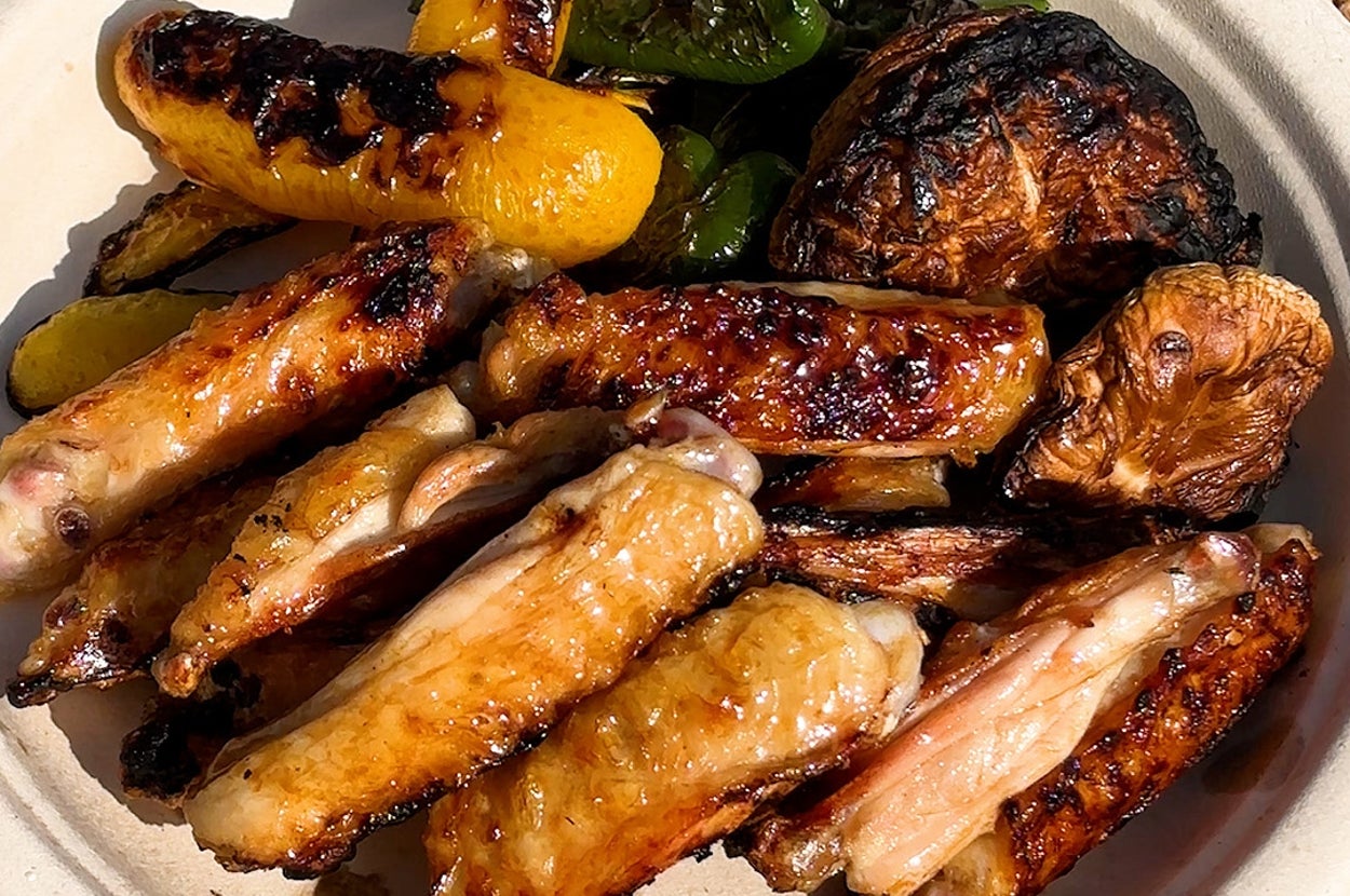 鶏手羽と野菜の盛り合わせが皿にのっている。手羽は照りがあり、焼かれた野菜も見える。