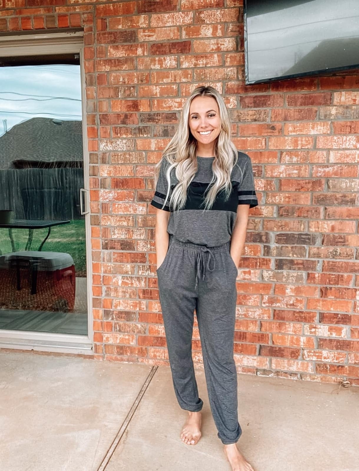Person lasting  barefoot connected  a patio, wearing a casual lounge acceptable   with abbreviated  sleeves and joggers, leaning against a ceramic  wall