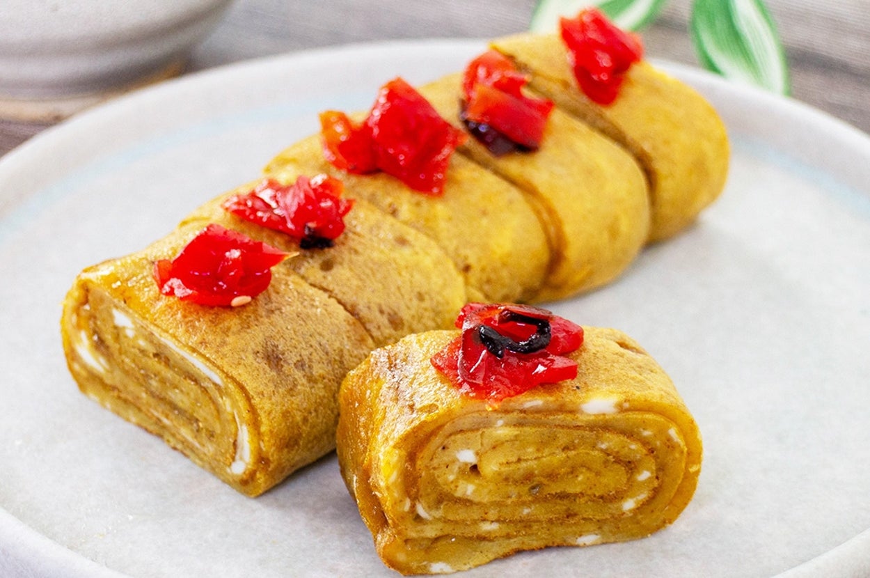 お皿に盛られた卵焼きの上に野菜が散らされている。