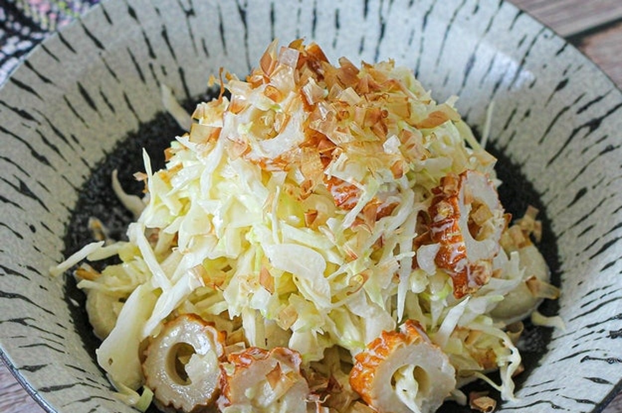白い陶器の皿に盛られたキャベツとちくわのサラダ、上に削り節がトッピングされている。