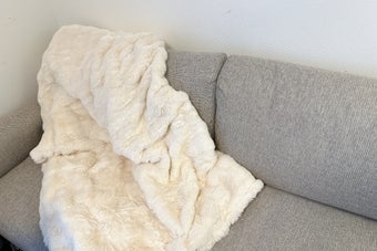 ソファに白いふわふわのブランケットが掛かっている様子。