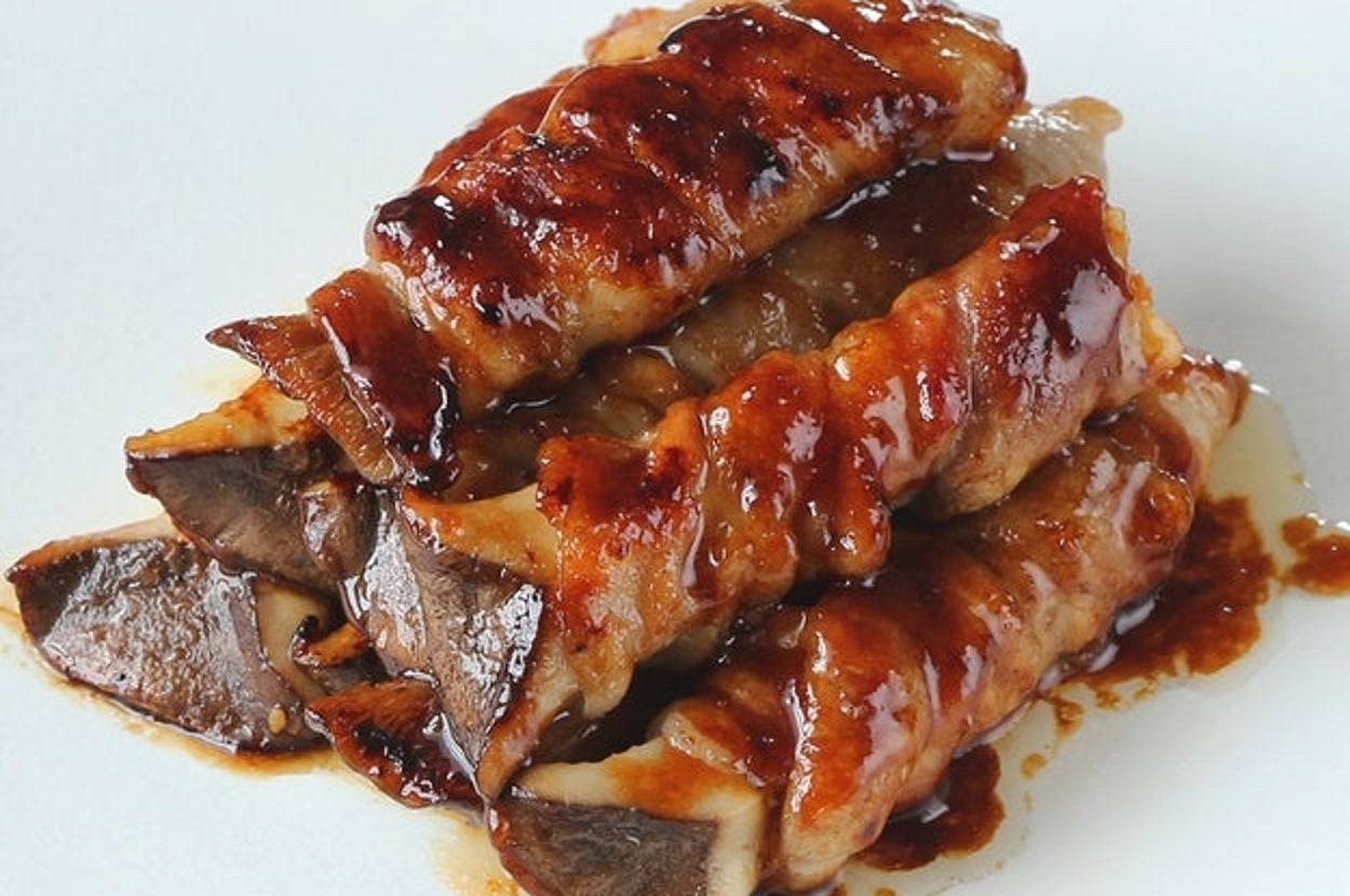 キノコをベーコンで巻いた料理が積み上げられ、照り焼きソースがかかっている。シンプルで美味しそうなプレゼンテーション。