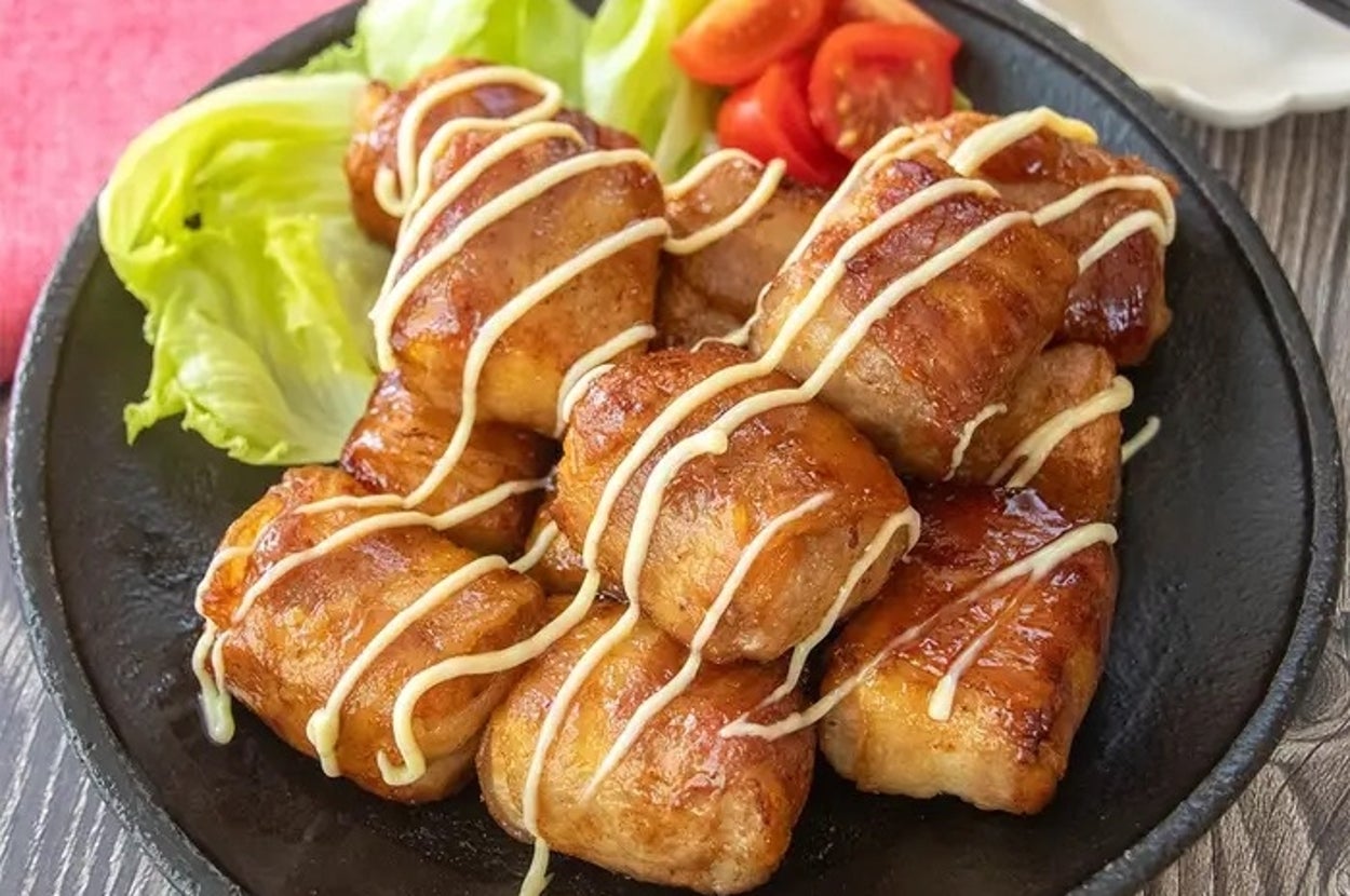 焼き豆腐の串焼きにマヨネーズがかかった料理。レタスとプチトマトを添えた黒い皿に盛られています。