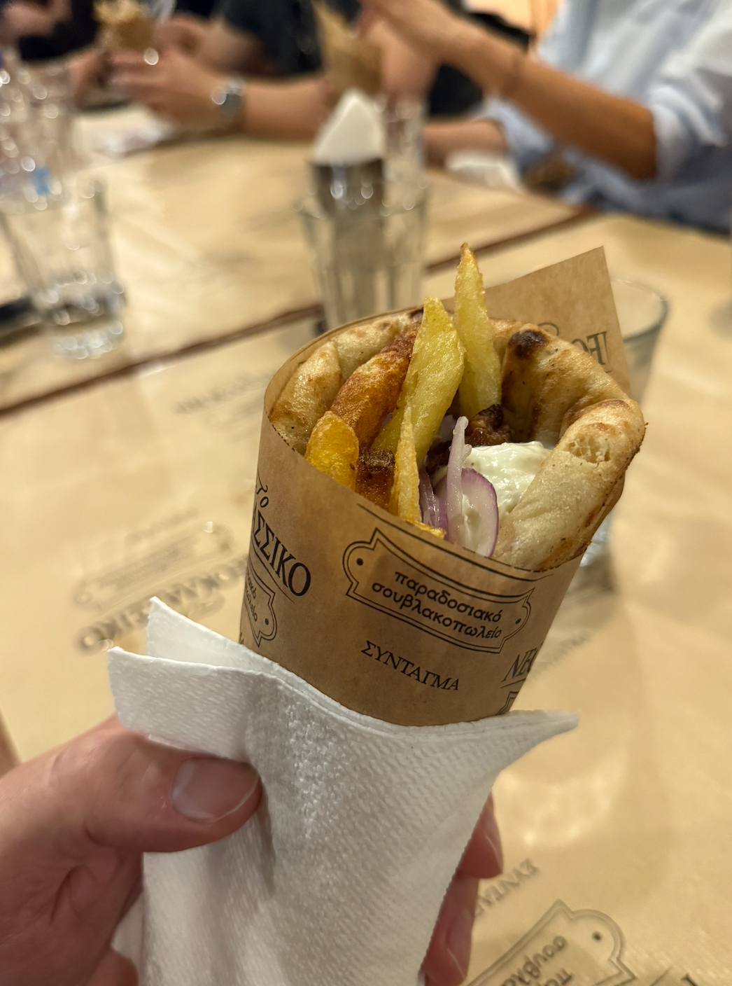 holding a gyro in pita in front of a large dining table