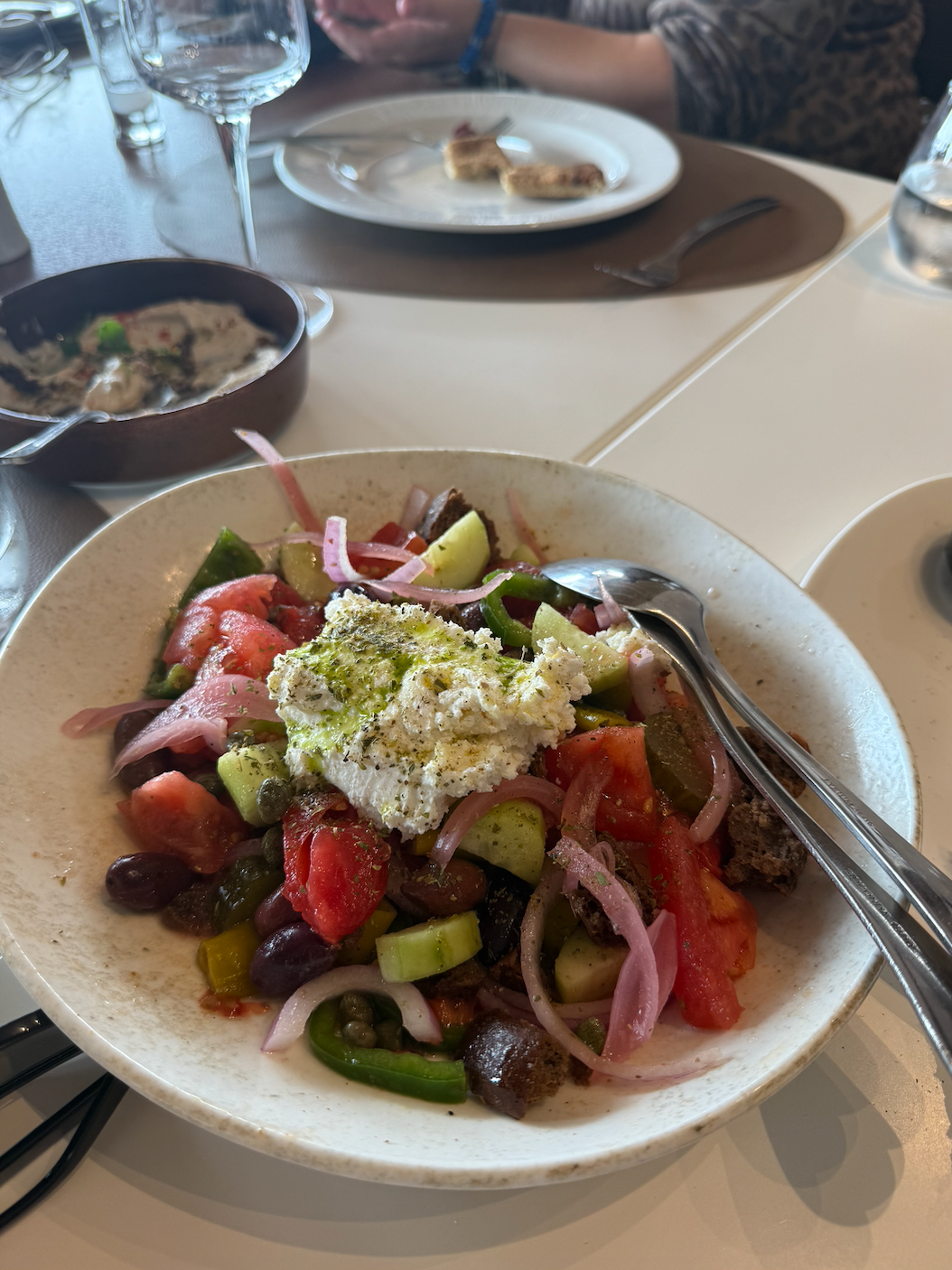 A plate of Greek salad with tomatoes, cucumbers, olives, sliced onions, and feta cheese
