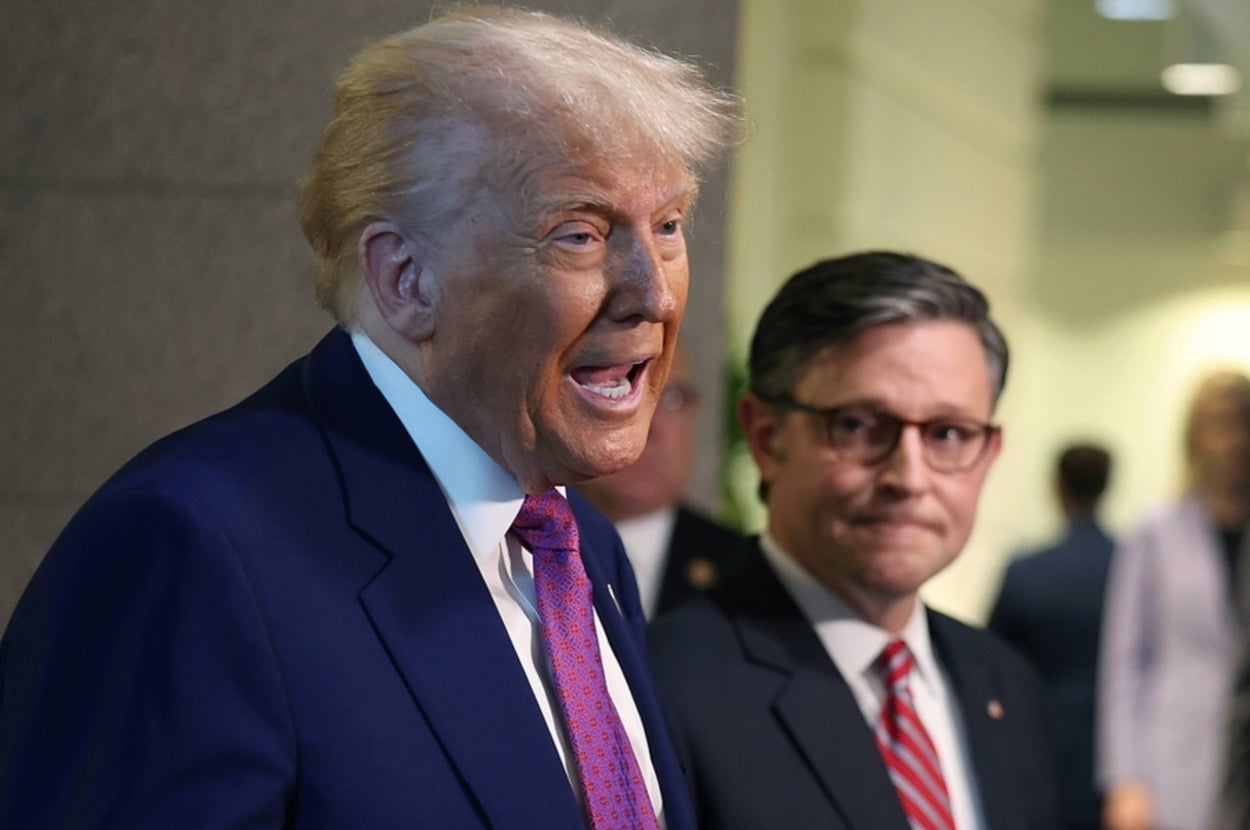 スーツ姿の二人の男性が話をしている。背景に数名の人々が見える。