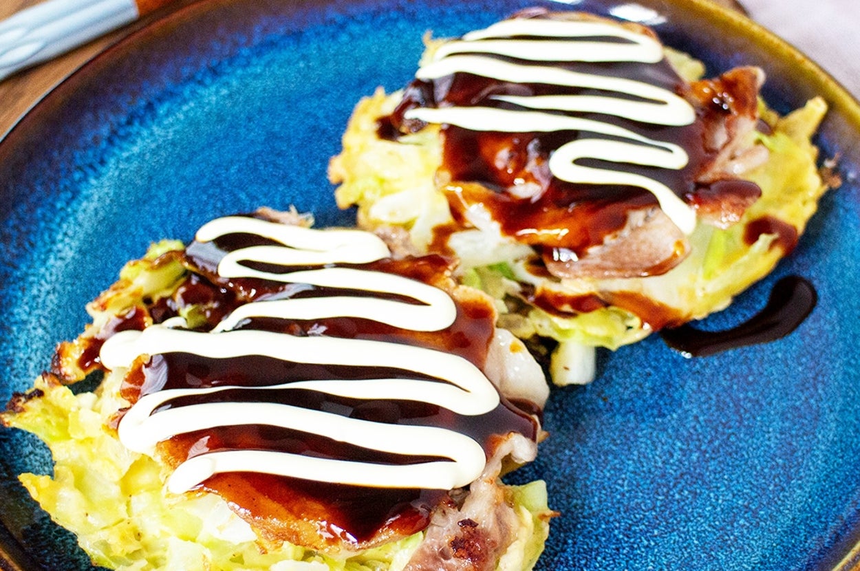 お好み焼きが2枚、ソースとマヨネーズがかかっている青い皿に盛られている。