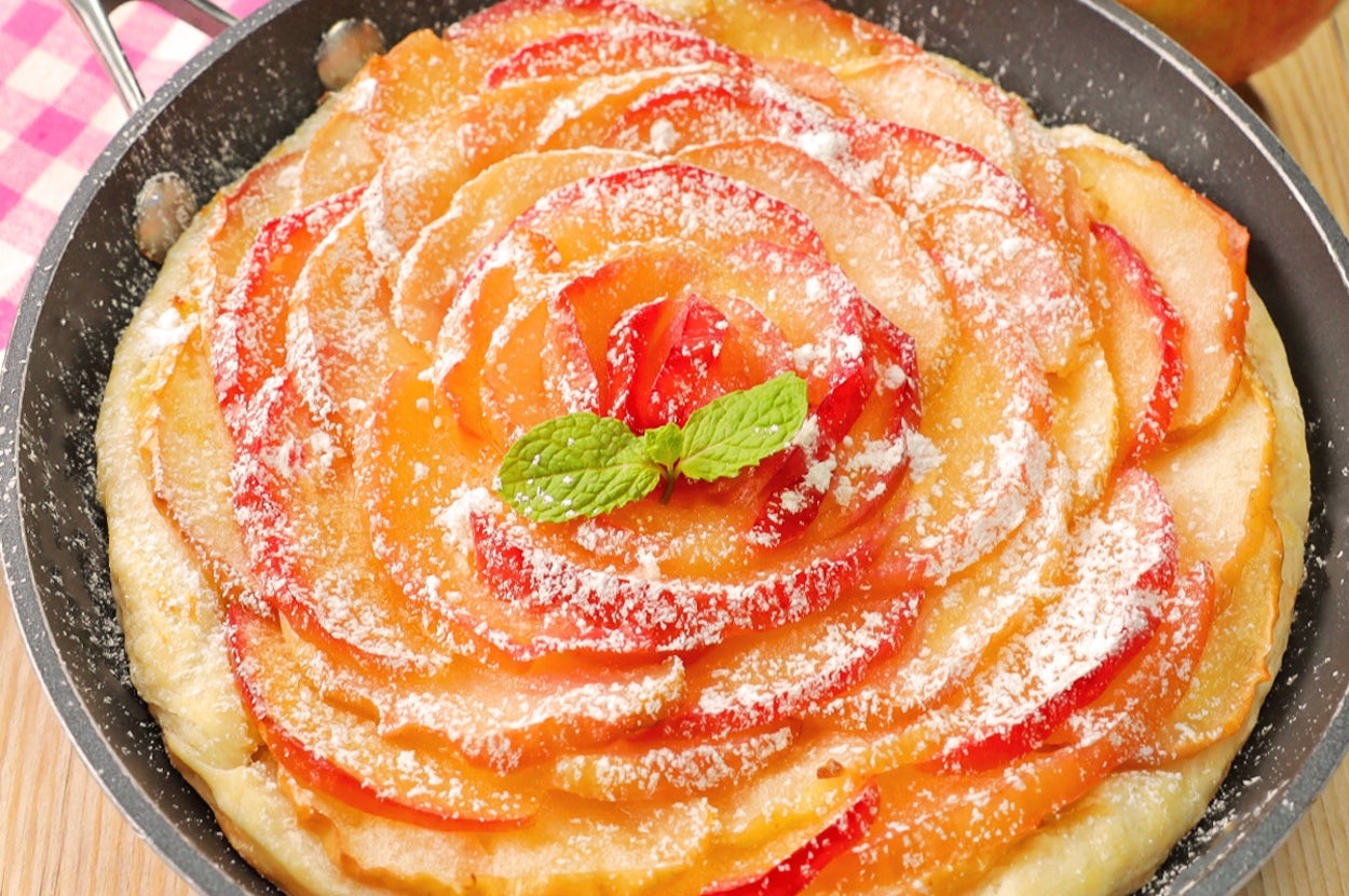 フライパンに盛り付けられたアップルタルト。粉砂糖とミントの葉が飾られています。