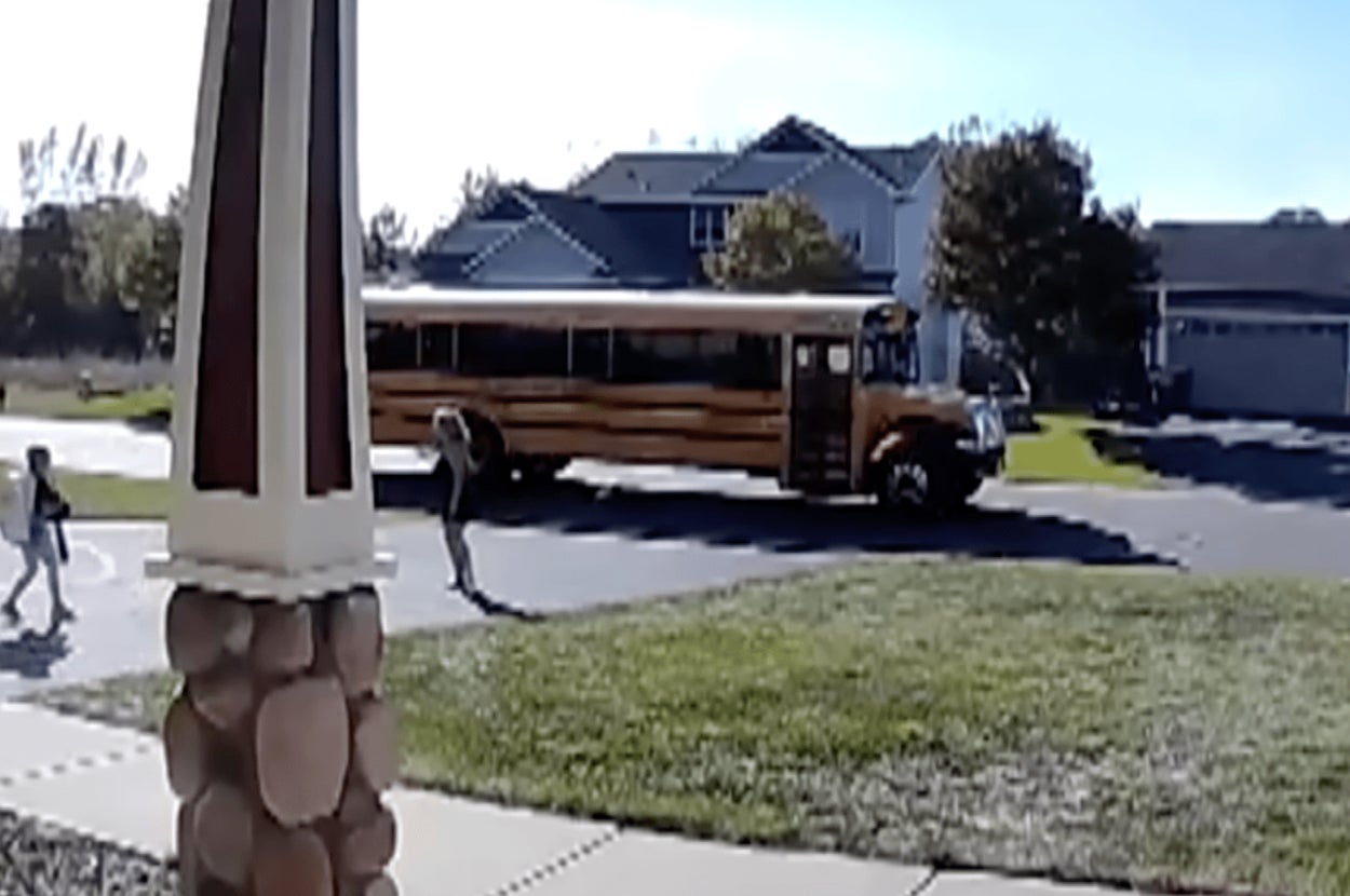 住宅街で停車中のスクールバスから子供たちが降りて家に向かう様子。