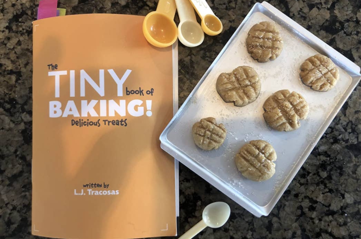 Baking book with cookies on a tray, accompanied by measuring spoons