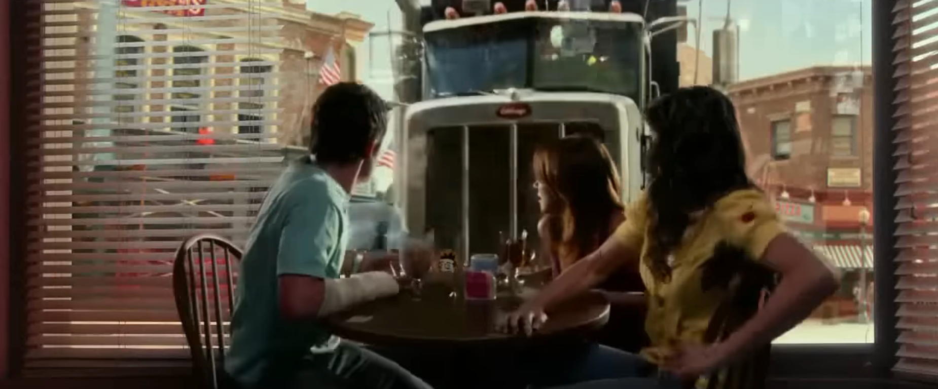  3  radical   are startled by a motortruck  crashing into a diner, viewed from inside