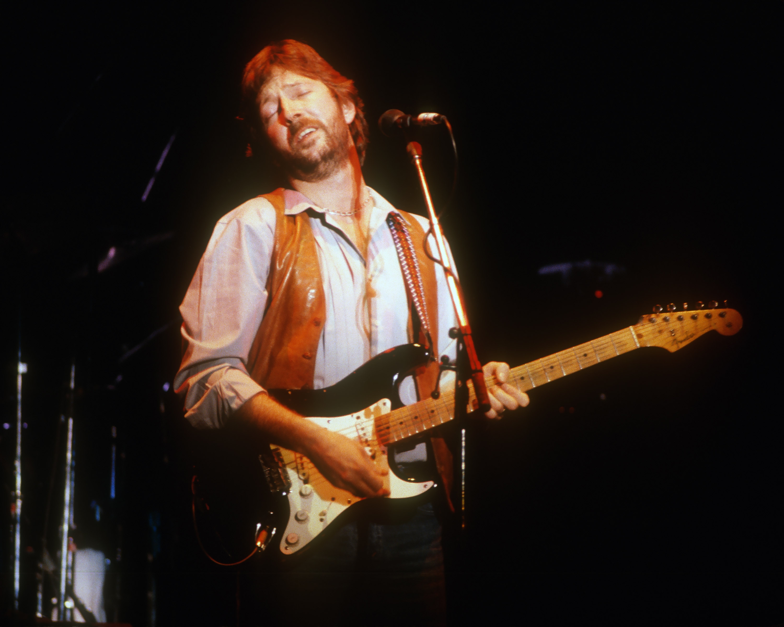 Musician performing connected  signifier    with electrical  guitar, wearing a fringed vest implicit    a button-down shirt, eyes closed, conveying heavy  emotion