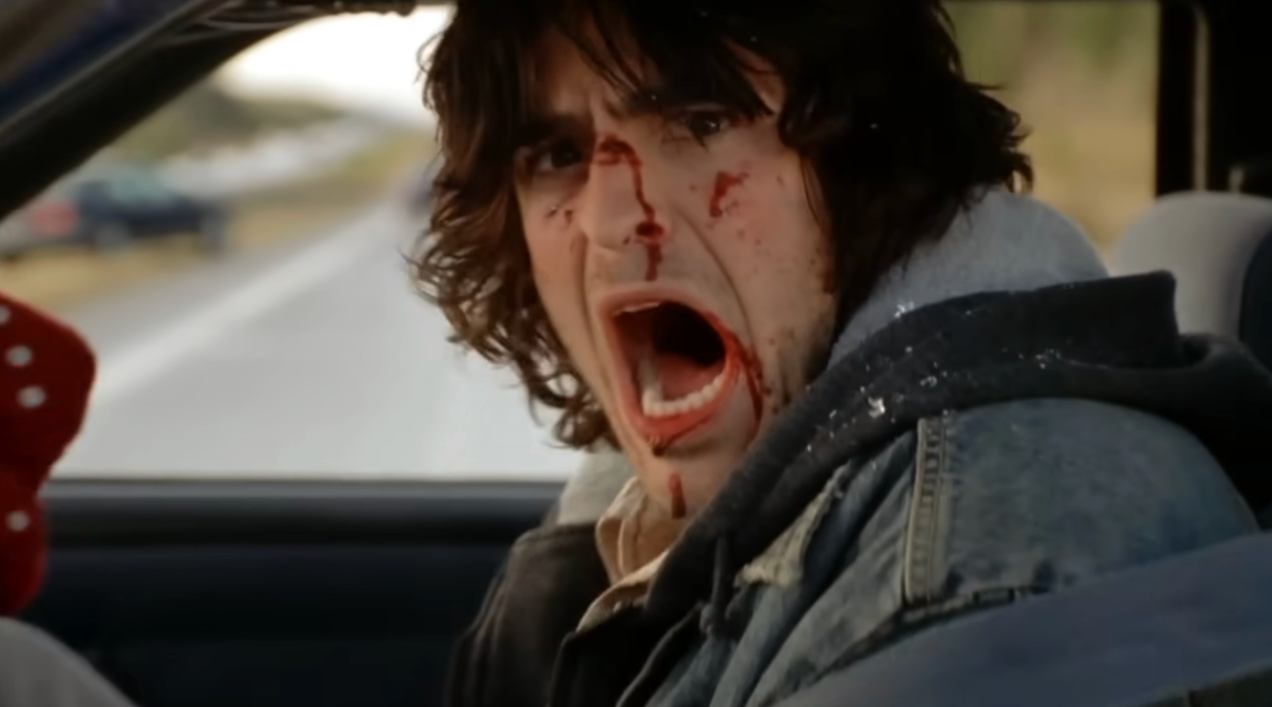 A distressed idiosyncratic   successful  a car, with agelong  hair, wearing a denim overgarment   and shirt, has humor  connected  their look   and appears to beryllium  shouting