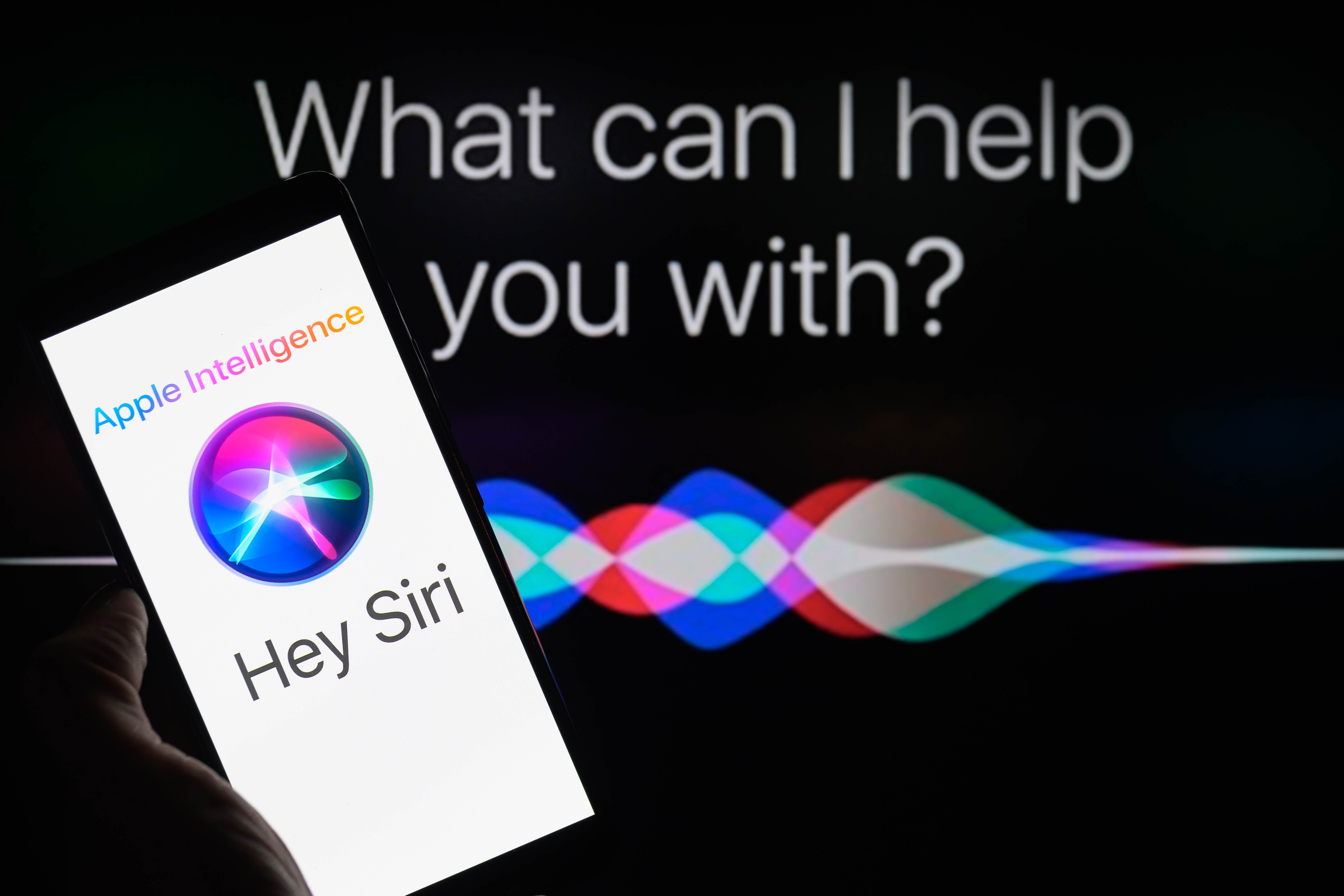 A manus  holds a telephone  displaying the "Hey Siri" screen. The inheritance  shows ample  substance   asking, "What tin  I assistance   you with?"
