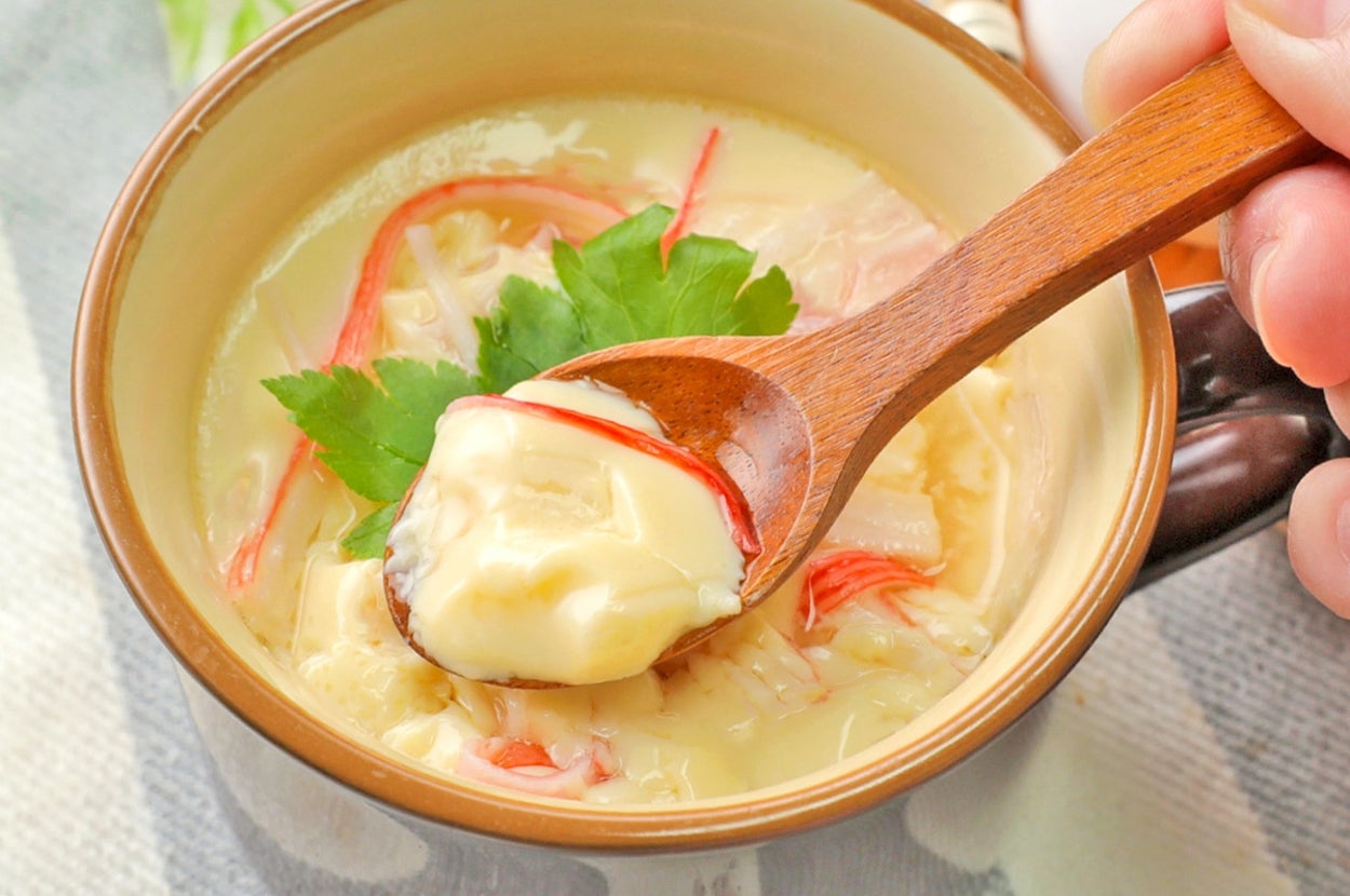 茶碗蒸しがスプーンですくわれている様子。上にカニカマとパセリが載っている。