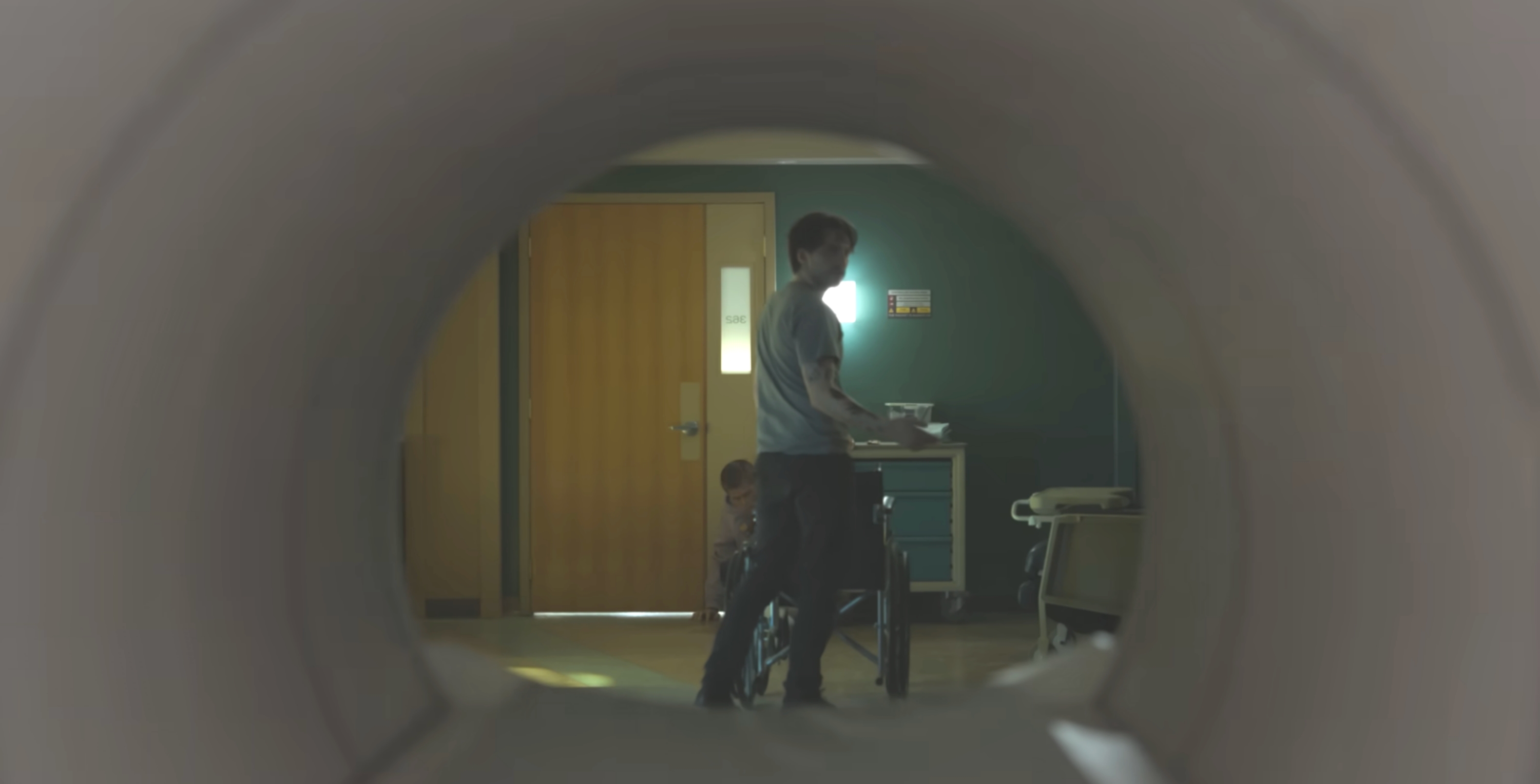 A idiosyncratic   lasting  adjacent  to a kid  successful  a dimly lit room, viewed from wrong  aesculapian  equipment, suggesting a infirmary  oregon  aesculapian  setting