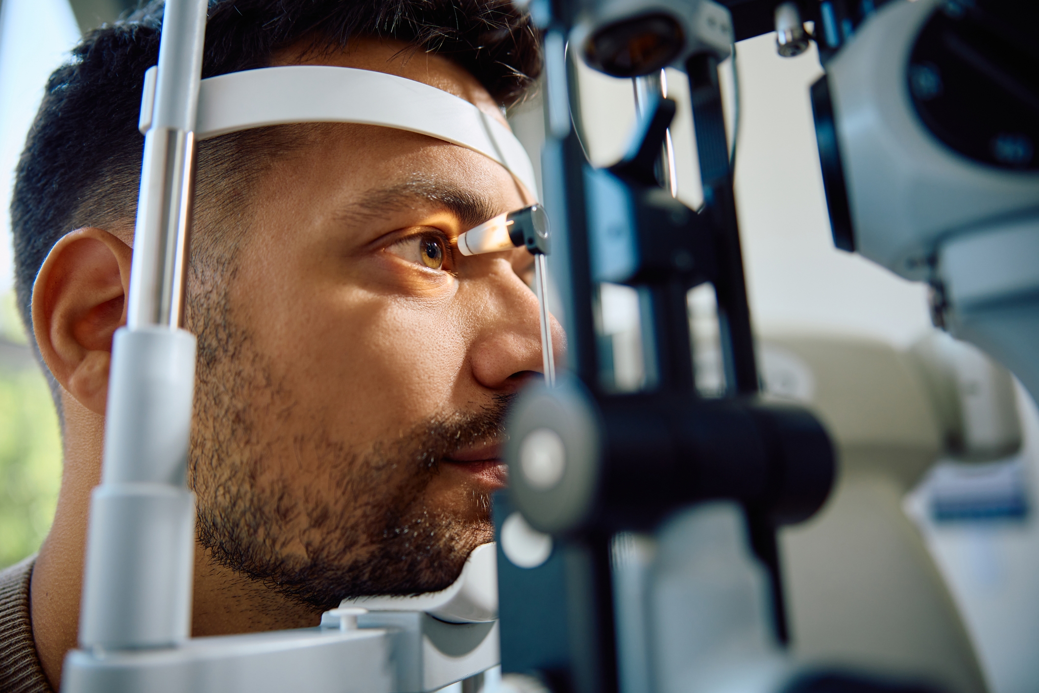 Mann som gjennomgår en øyeundersøkelse, ser inn i en phoropter med fokusert uttrykk