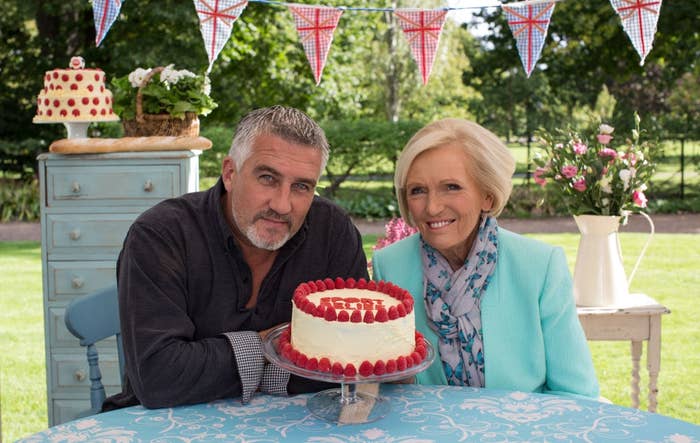 Great British Bake off judges, Mary Berry and Paul Hollywood pose in front of a cake