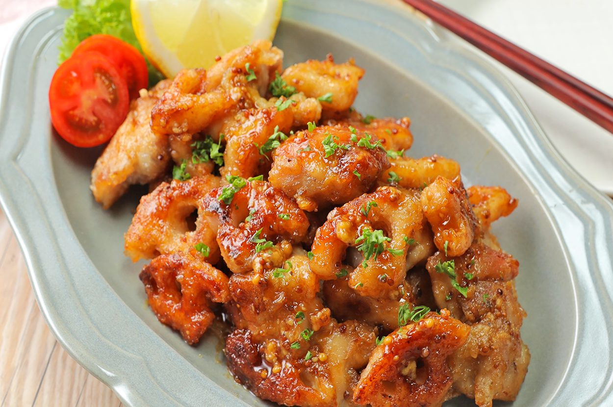 皿に盛り付けられた焼き鳥の料理。レモン、トマト、レタスが添えられており、おいしそうに見える。