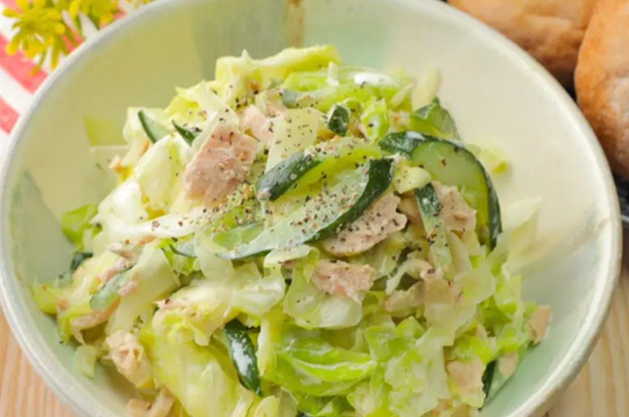 ハーブで飾られたツナと野菜のサラダがボウルに盛られている。横にパンが添えられている。