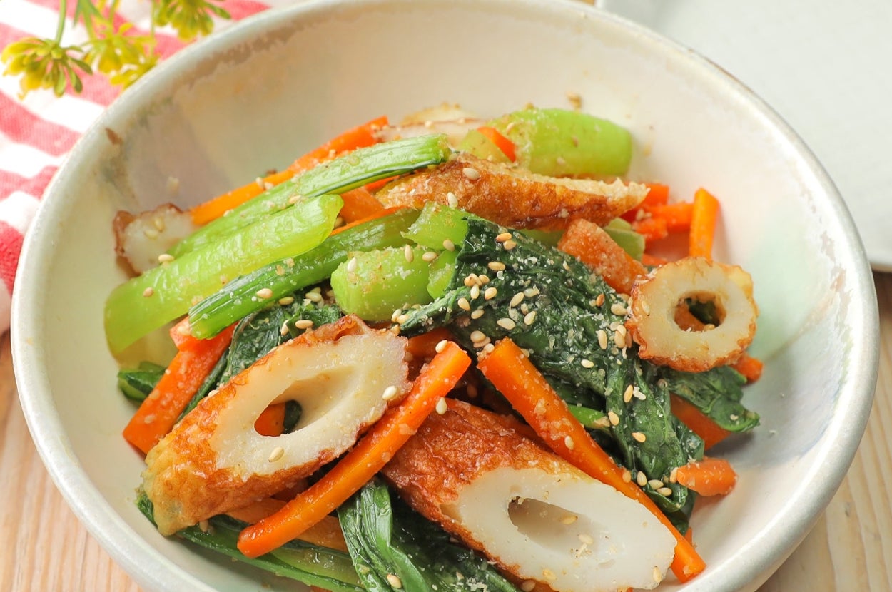 野菜とちくわの炒め物。にんじん、緑野菜、ちくわが皿に盛られている。ごまがトッピングされている料理。