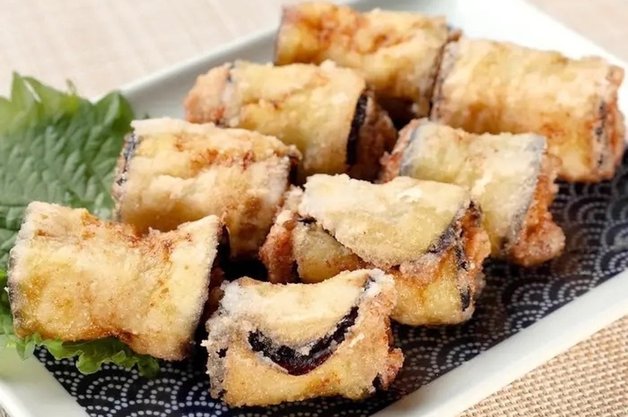 皿の上に盛り付けられた揚げたナスの料理。付け合わせの葉が添えられている。