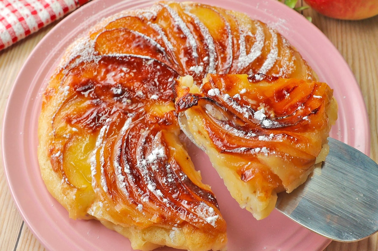 デザートプレート上の焼きりんごタルト、キャラメリゼされ粉砂糖がかかっている。