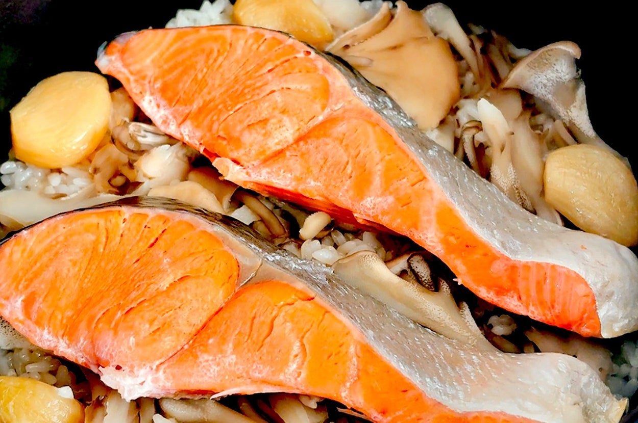 サーモン切り身ときのこ、にんにくがご飯の上に乗った鍋料理。