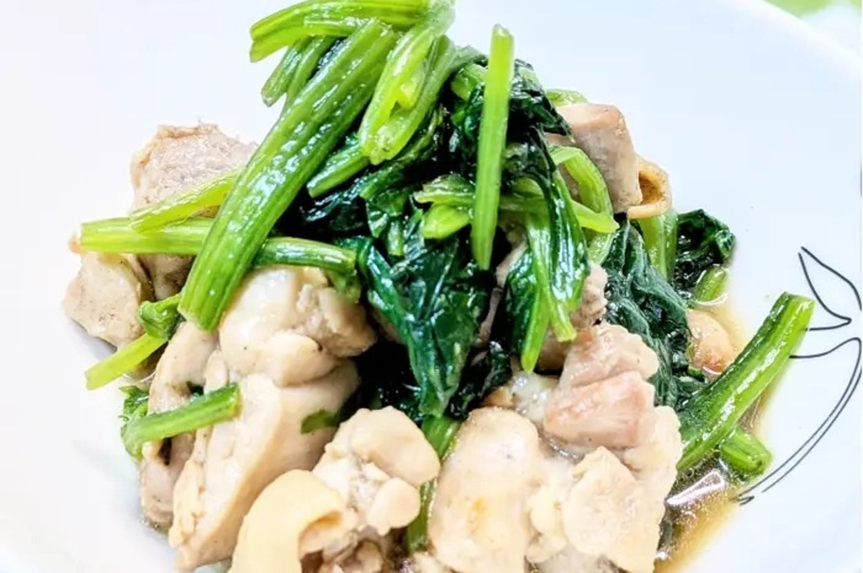 皿に盛られた煮込み料理。鶏肉と緑の葉物野菜が混ざり合った食事のイメージ。