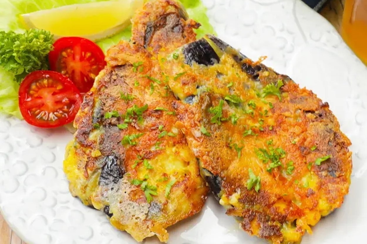 皿に盛り付けたナスのチーズ焼き。レタス、トマト、レモンが添えられている。