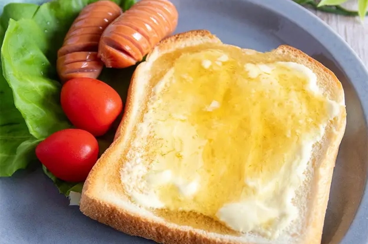 トーストにマヨネーズとハチミツ、ソーセージ2本、トマト、レタスが添えられたプレート。