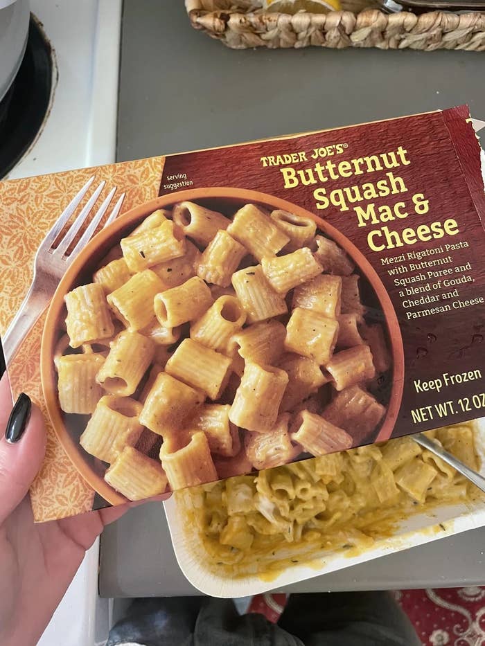 Trader Joe&#x27;s frozen Butternut Squash Mac &amp;amp; Cheese packaging held above a partially eaten serving in a tray