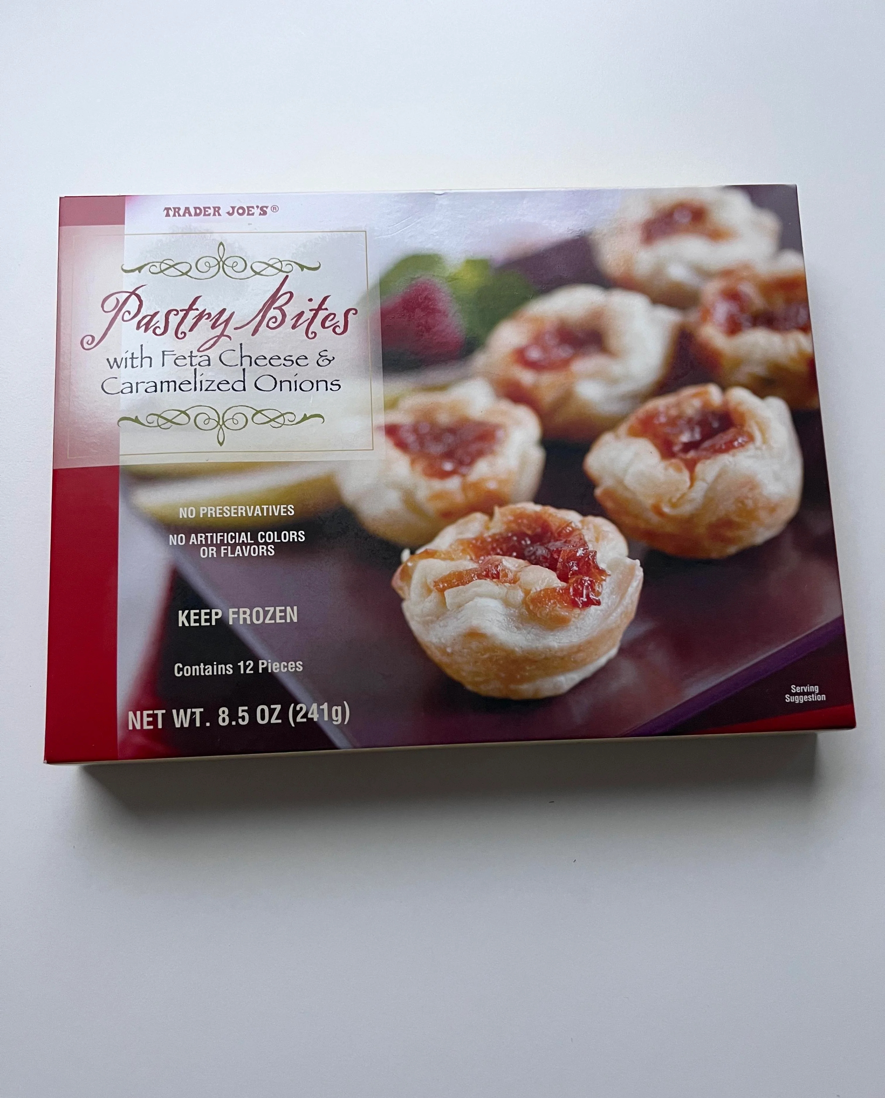A box of Trader Joe&#x27;s Pastry Bites with Feta Cheese and Caramelized Onions, showing appetizing baked pastries on the packaging