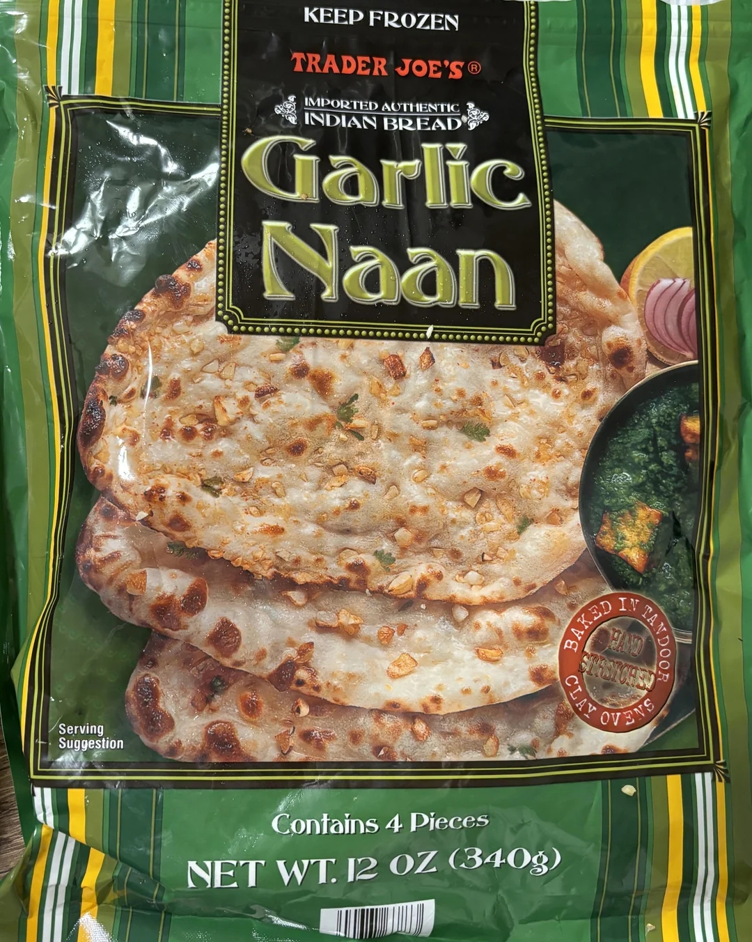 Trader Joe&#x27;s Garlic Naan packaging showing four pieces with garlic bits and suggestion to bake in a tandoor clay oven. Net weight: 12 oz (340g)