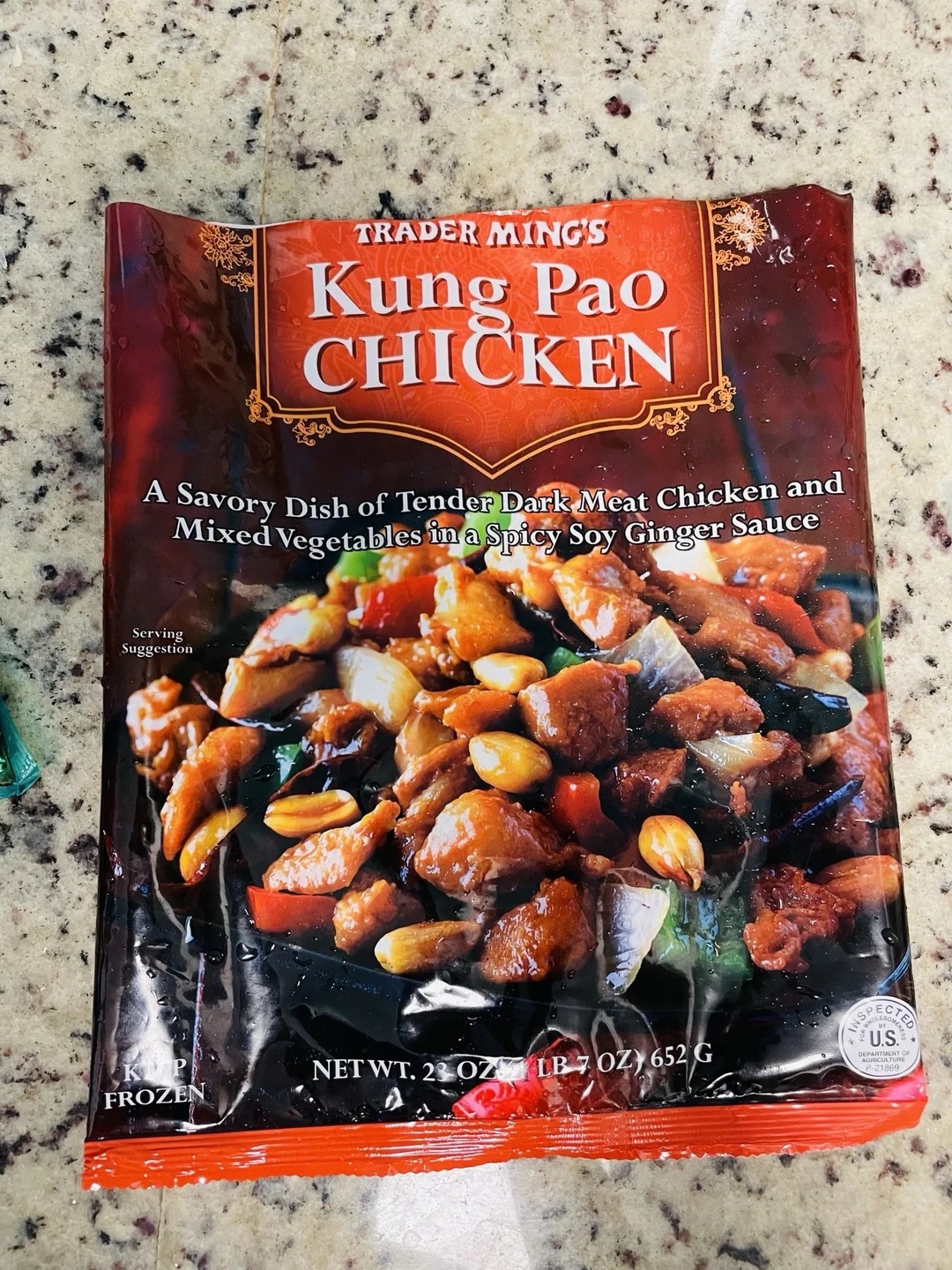 Trader Ming&#x27;s Kung Pao Chicken package on a countertop. Describes a savory dish with dark meat chicken and mixed vegetables in spicy soy ginger sauce