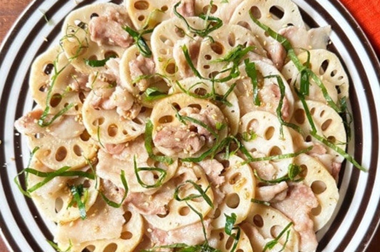 れんこんと豚肉の炒め物が皿に盛られ、薄切りのしそがトッピングされています。