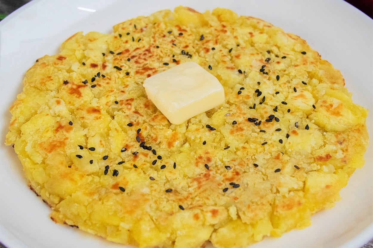 お皿に盛られたハッシュドさつまいも。中央にバターがのり、黒いりごまがトッピングされています。