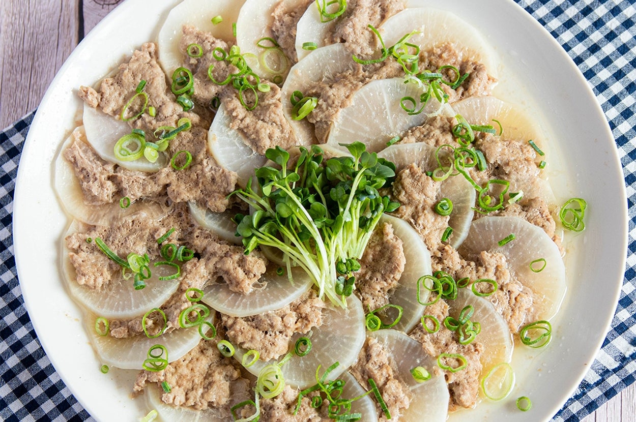 大根のスライスにひき肉とねぎのトッピングがされた料理が白い皿に盛られている。