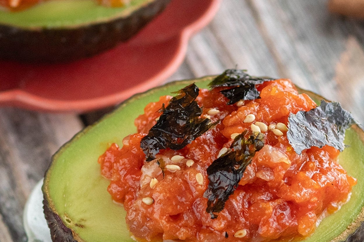 アボカド半分にスパイシーツナ、ゴマ、海苔をトッピングした料理が小皿に載っている。