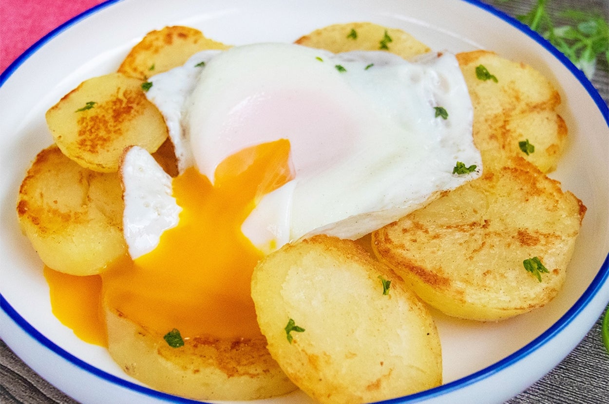 目玉焼きが半熟で割れ、ポテトの上に乗っている料理。シンプルな盛り付け。