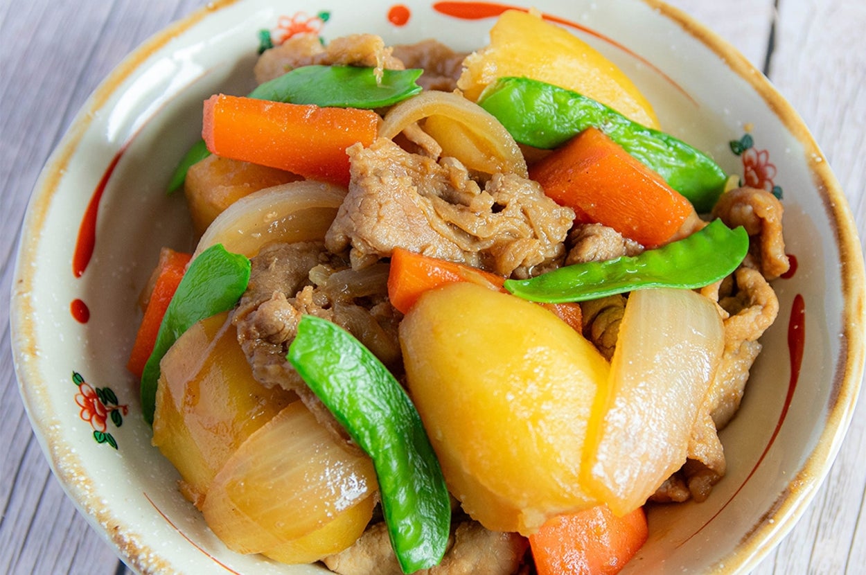 和風の肉じゃがが盛り付けられた陶器の器。肉、玉ねぎ、じゃがいも、人参、絹さやが見える。